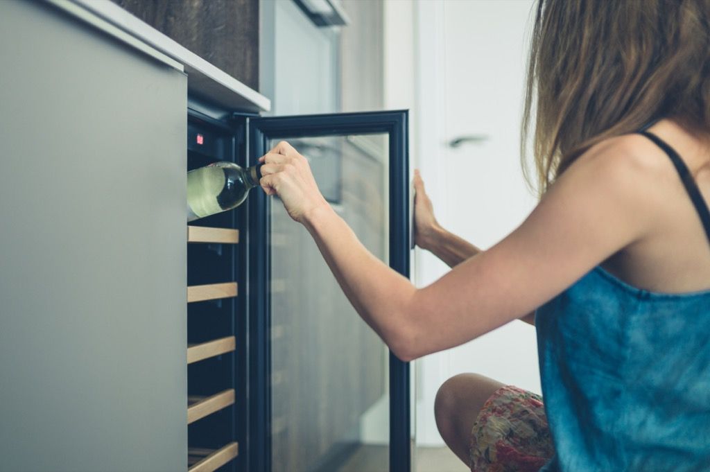 Женщина тянется к винному холодильнику, домашние обновления