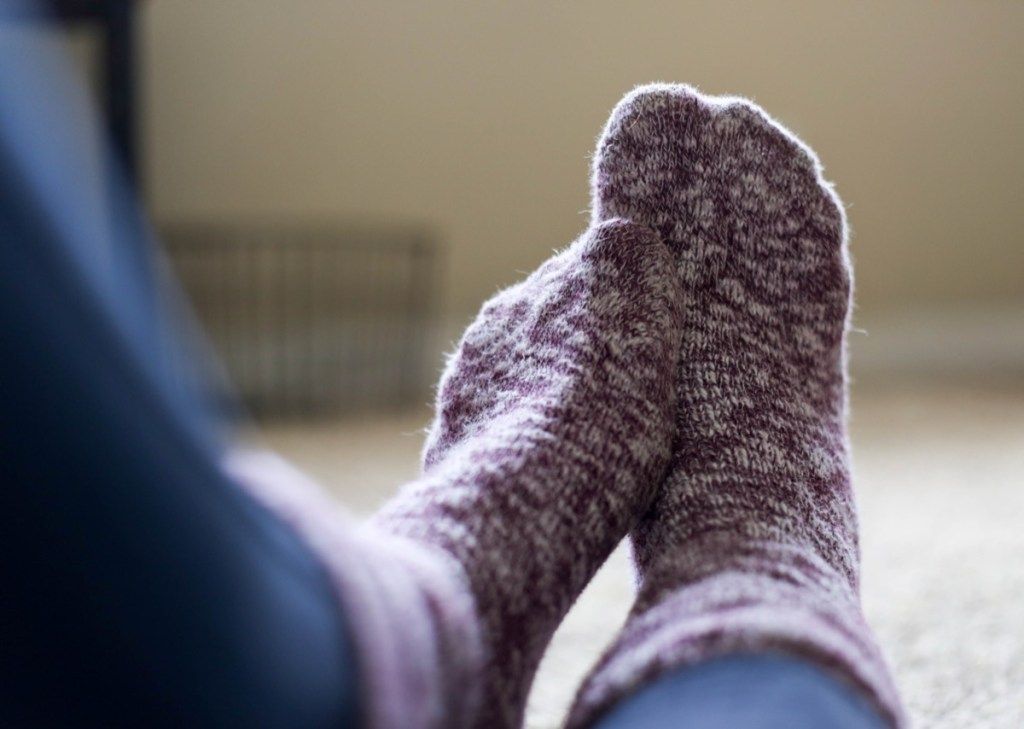 Frau, die Fuzzy-Socken trägt, die Füße schmerzen
