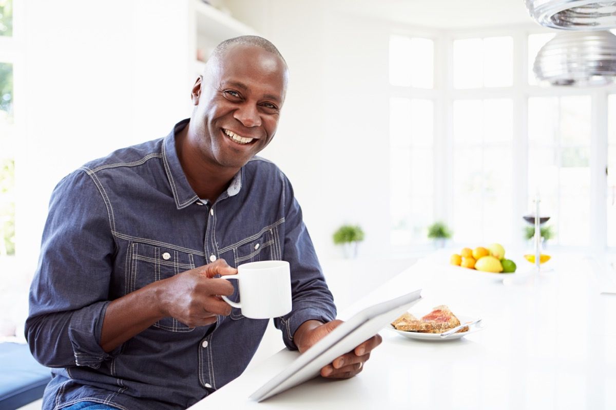 mężczyzna trzyma kawę uśmiechnięty ze śniadaniem