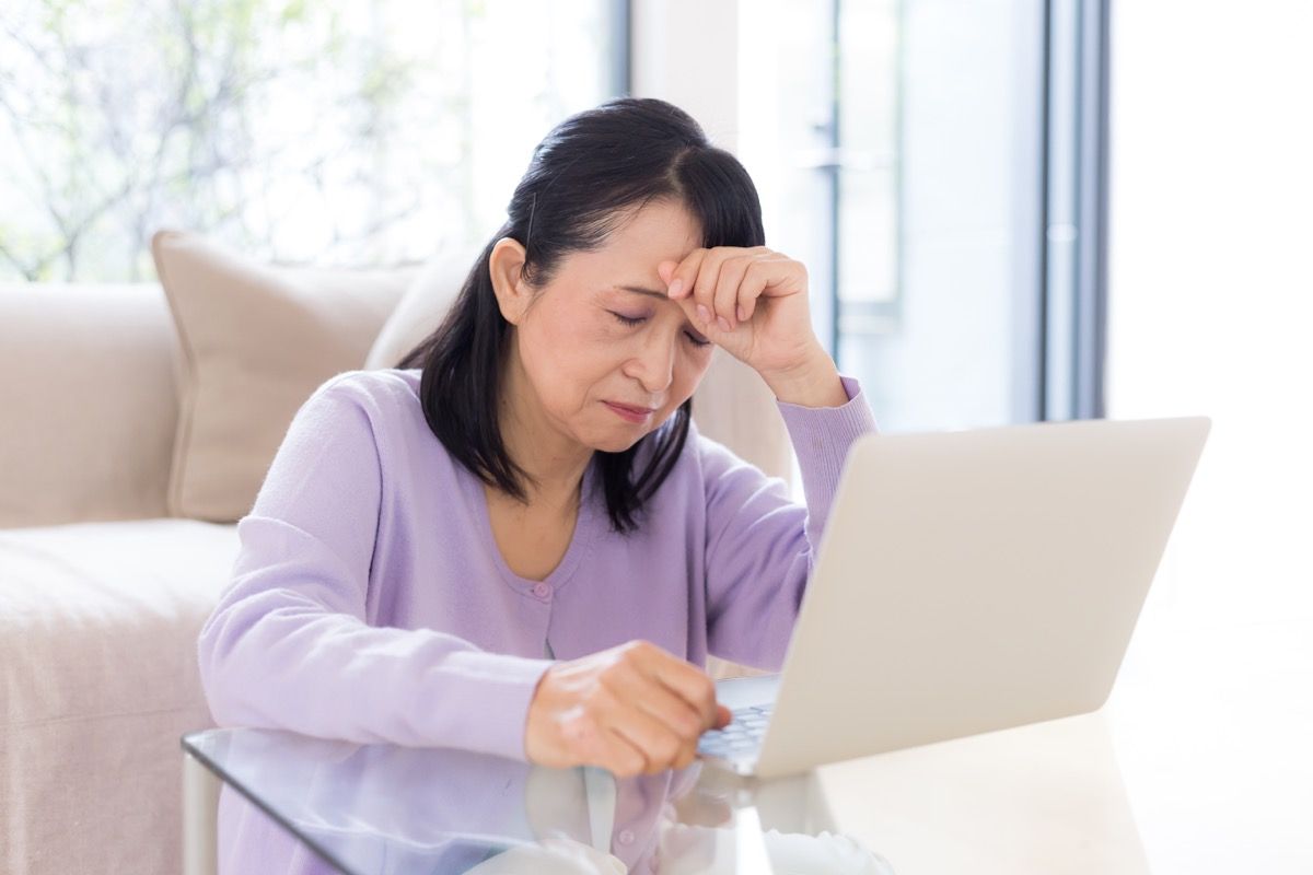 mujer con dolor de cabeza en una computadora portátil