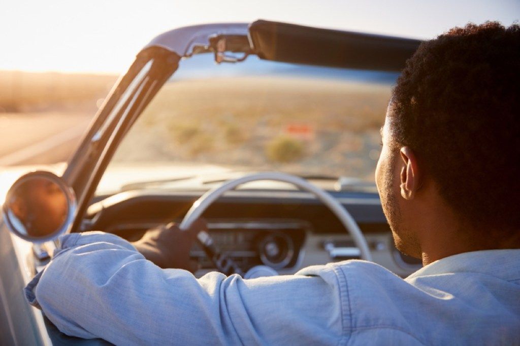 portré hátulról a fekete ember, aki kabriót vezet a sivatagban, 40 felett változik