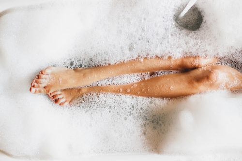   ஒரு பெண்ணின் படம்'s legs in a bubble bath