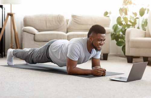   muž dělá online cvičení ve svém obývacím pokoji