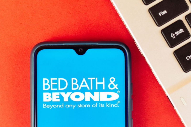   gultas vanna un ārpus tās tīmekļa vietne, kas parādīta viedtālruņa ekrāna tuvplānā, zilā fonā ar baltu fontu