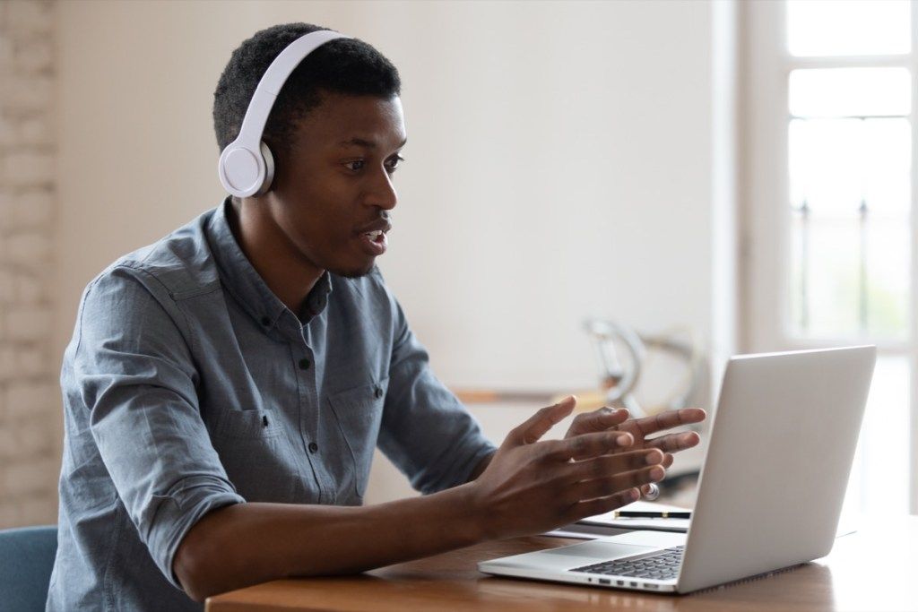 nuori musta mies yllään kuulokkeet videopuhelussa