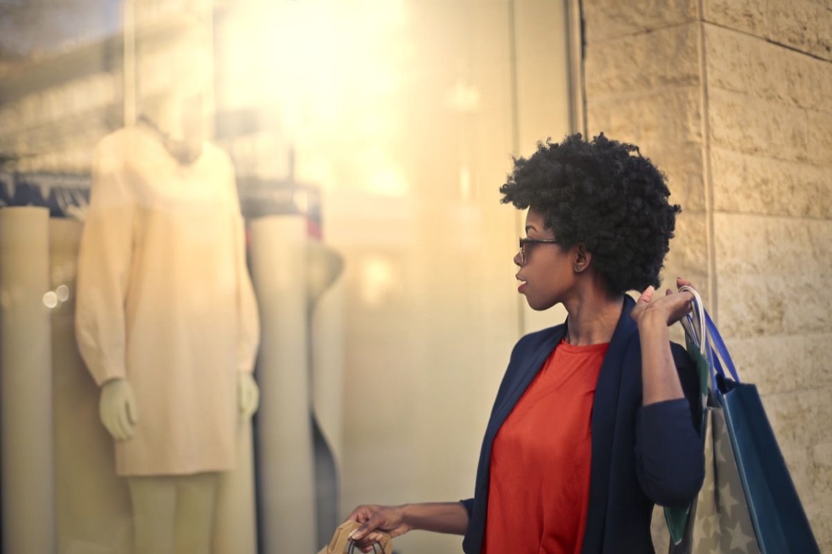 молодая темнокожая женщина смотрит в витрину магазина