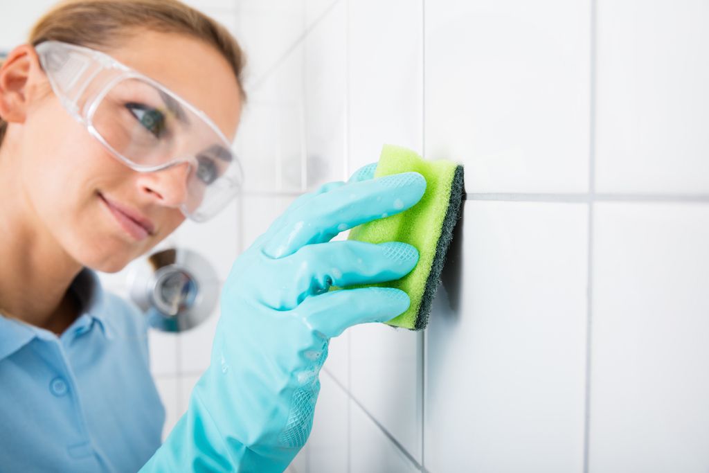 Žena čištění spárovací hmoty na stěnách dlaždic, čištění chyb