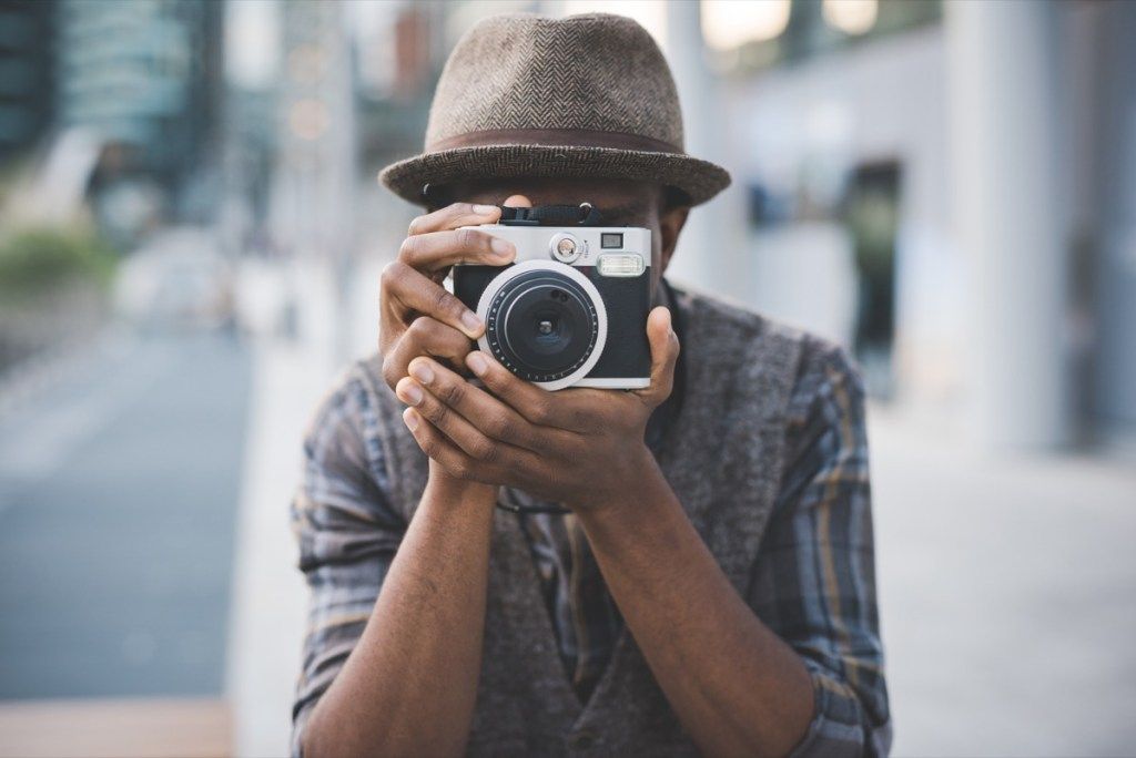 Пола дужине младог лепог афро црнца на отвореном у граду који држи тренутну камеру, снимање - фотографија, креативан, уметнички концепт - слика