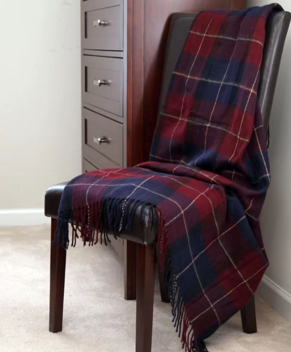 raudona ir mėlyna languota antklodė, užklijuota ant odinės kėdės