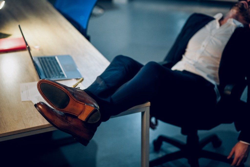 hombre pateando sus pies sobre un escritorio y durmiendo en la oficina