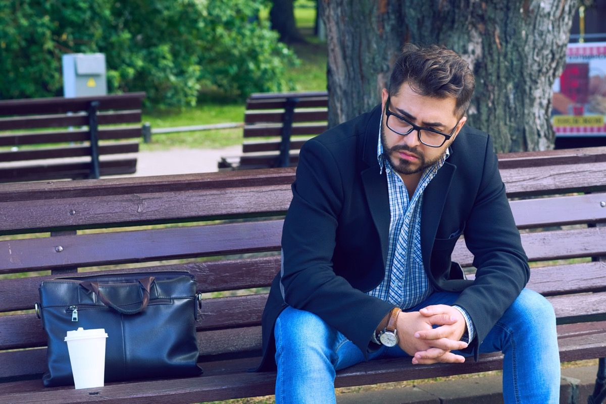 nuori mies lasit istuu penkillä puistossa surullinen ilme. Toimistotyöntekijä menetti työpaikkansa. Keski-ikäinen mies epätoivoinen talouskriisi.