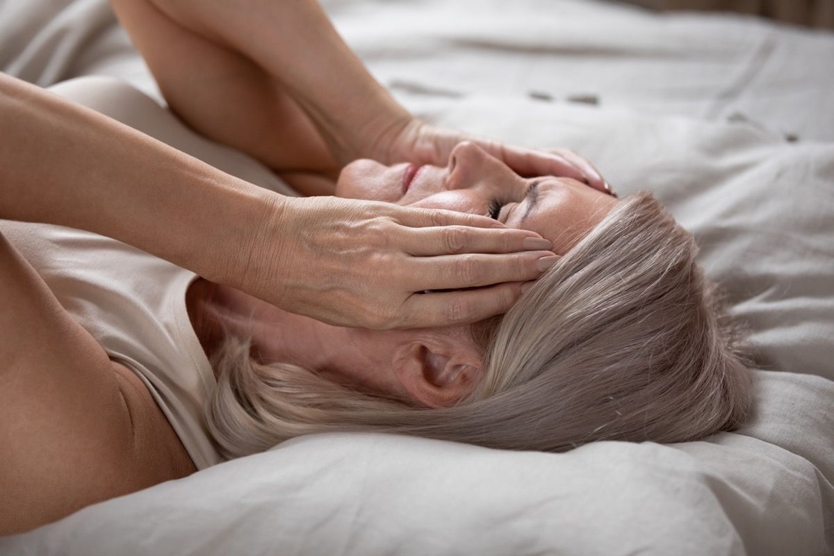 Stressi nainen koskettaa kasvojaan sängyssä
