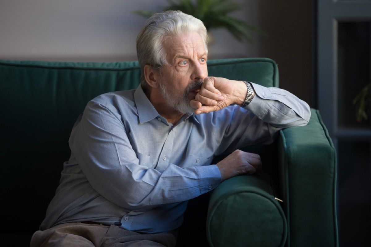 om în vârstă preocupat, așezat pe canapea