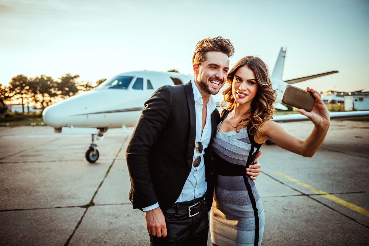 bohatý a slavný pár pořizující selfie před soukromým letadlem