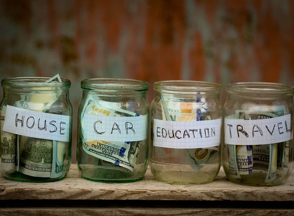 neli selget purki, millele on märgitud dollar, topitud maja, auto, haridus ja reisimine