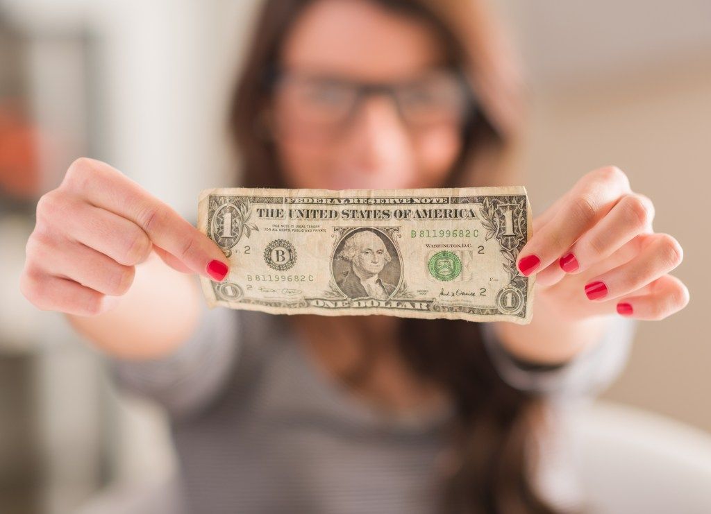 жена на фокус, която държи смачкана доларова банкнота пред камерата