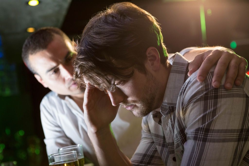El hombre revisa a un amigo estresado en el bar
