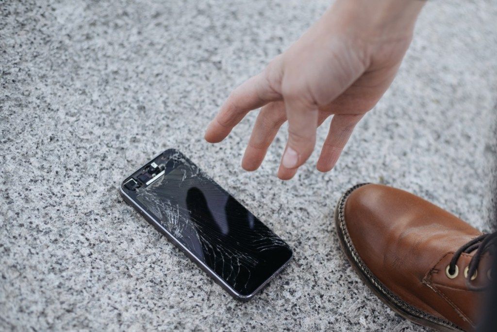người đàn ông nhặt điện thoại sau khi làm rơi nó xuống đất