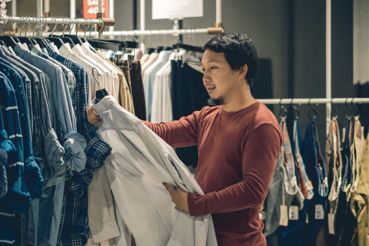 아시아 남자는 쇼핑하는 동안 셔츠를 본다
