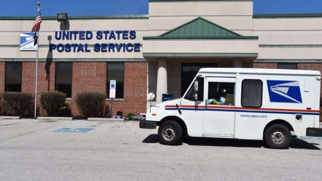   Крал на Прусия, Пенсилвания/САЩ-7 април 2020 г.: Камион на пощата на Съединените щати паркира пред сградата на пощата, за да вземе пощата по време на вируса COVID-19, тъй като те се считат за основен бизнес.