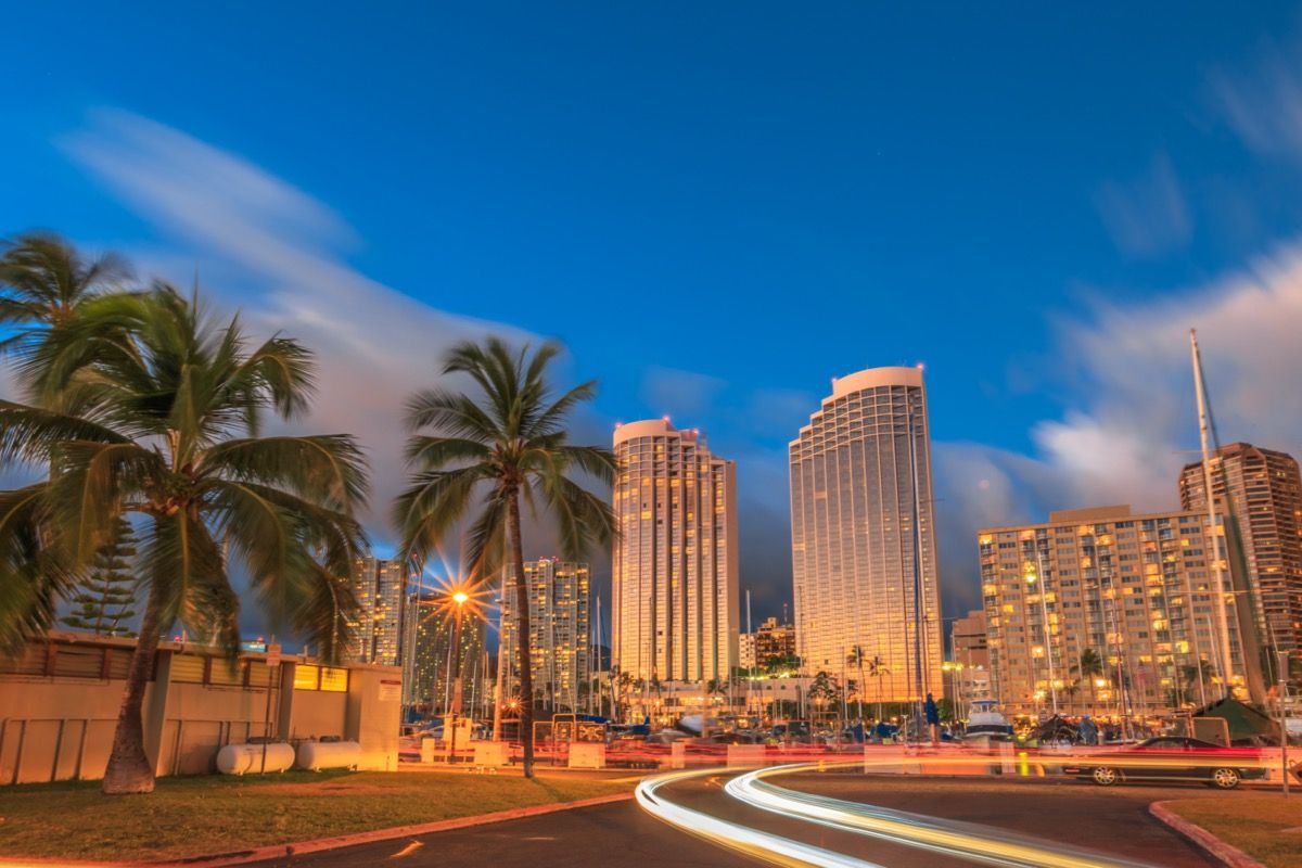 снимка на градски пейзаж на палми, сгради и бързо движещи се коли в Хонолулу, Хавай
