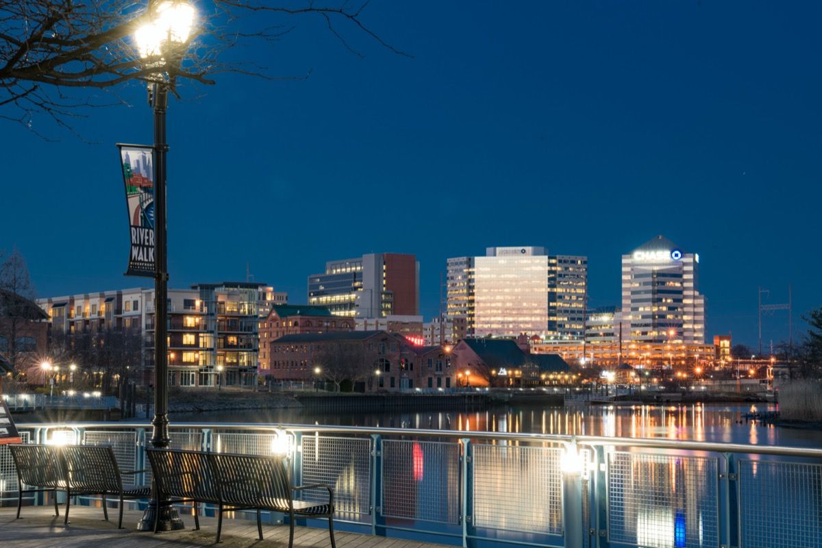 ภาพถ่ายทิวทัศน์เมืองของท่าเรือทะเลสาบและอาคารที่ River Walk Park ใน Wilmington, Delaware ในเวลากลางคืน