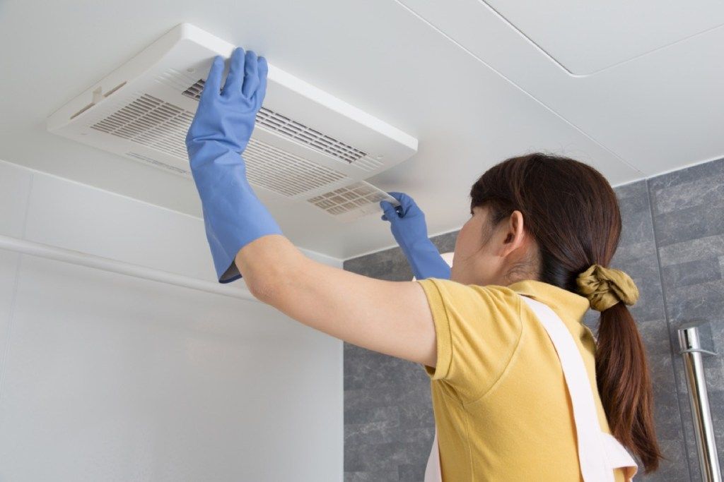 žena koja čisti ventilator za kupaonicu, znakove da se vaš dom raspada