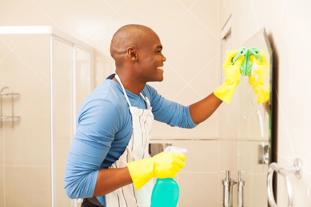 ชายผิวดำมีความสุขกับการทำความสะอาดกระจกห้องน้ำ