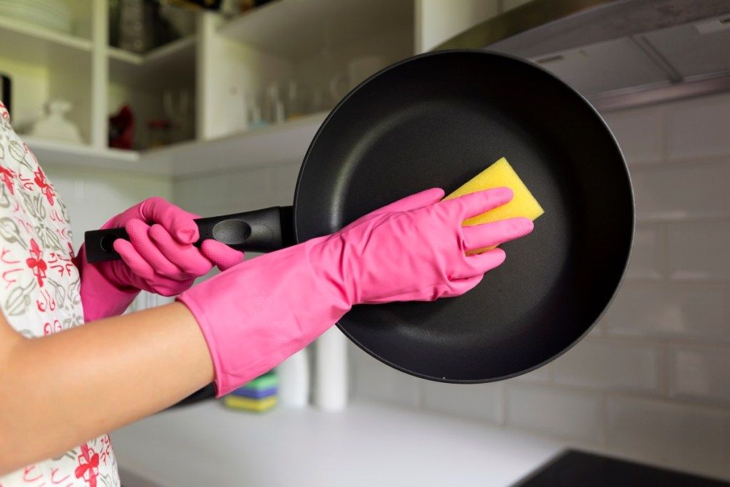 ผู้หญิงกำลังทำความสะอาดกระทะในอ่างล้างจาน