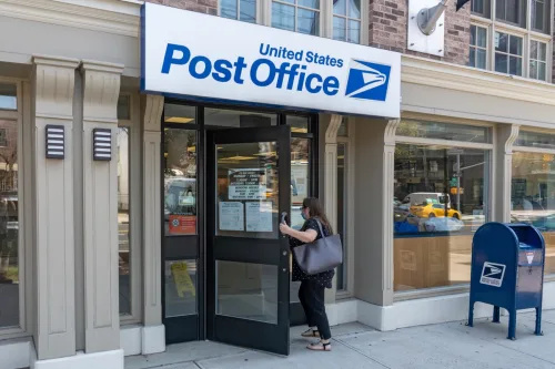   Một người phụ nữ bước vào bưu điện của Dịch vụ Bưu chính Hoa Kỳ (USPS) ở Thành phố Long Island vào ngày 17 tháng 8 năm 2020 tại Khu Queens của Thành phố New York.