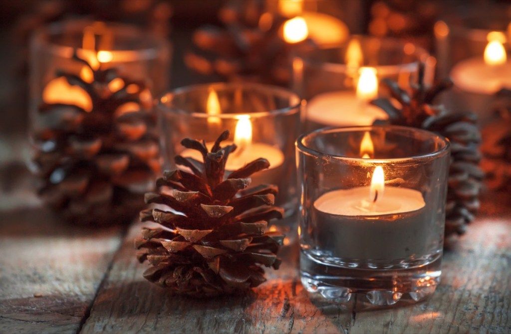 χριστουγεννιάτικα κεριά που περιβάλλονται από κουκουνάρια