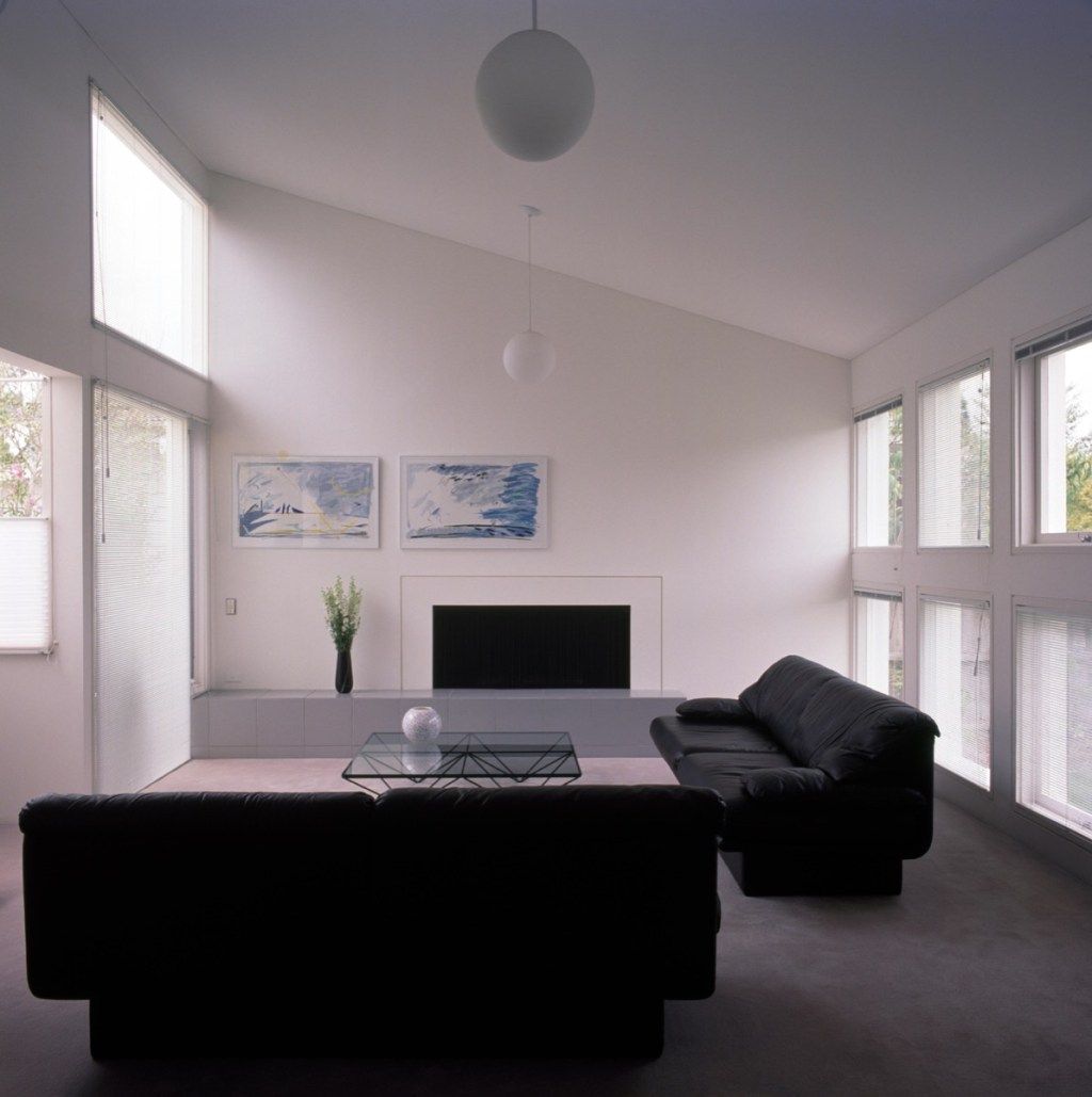 Sofás negros en una sala de estar blanca de estilo minimalista