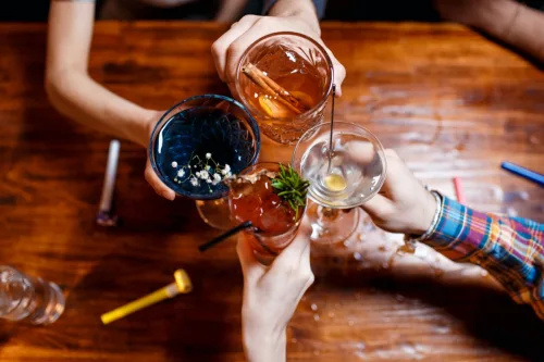   приятели, дрънкащи по чаши с различни алкохолни коктейли на масата, изглед отгоре в близък план