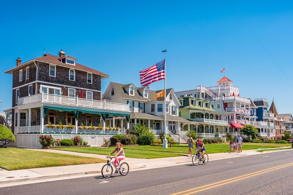 Folk sykler og går foran tradisjonelle villaer i Cape May, New Jersey, USA, på en solrik sommerdag.