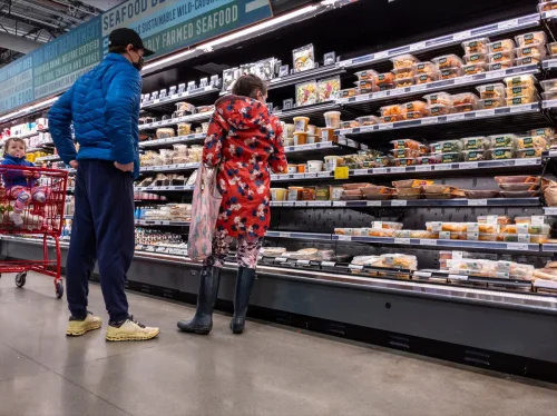   Whole Foods Market 내부의 준비된 음식 통로에서 아기를 안고 쇼핑하는 남녀의 모습