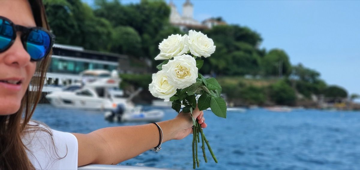 Młoda kobieta upuszcza białe kwiaty do oceanu
