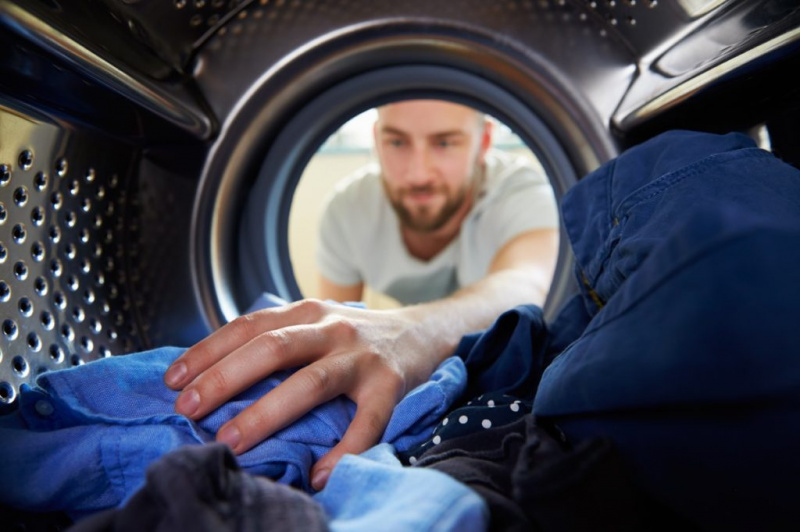   người đàn ông đang giặt quần áo màu xanh lam của mình