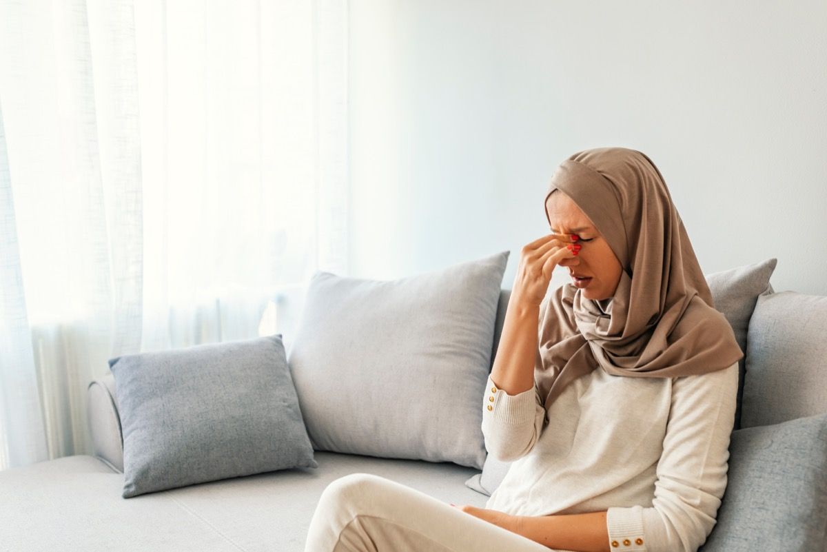 sorglig muslimsk kvinna i hijab på soffan
