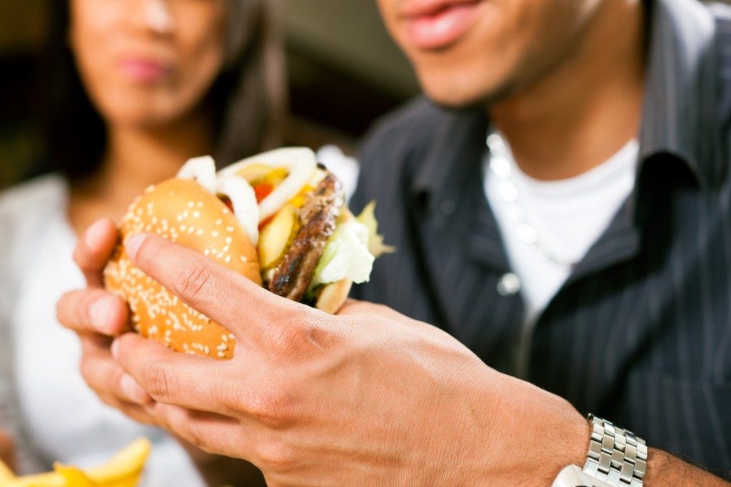 Vyras, valgydamas „Hamburger BBQ“ etiketo klaidas
