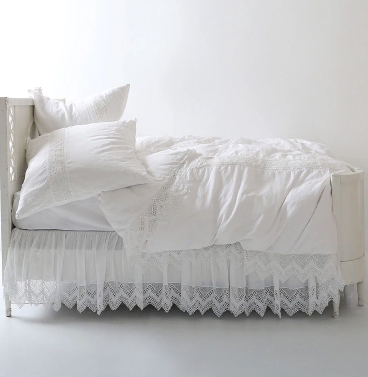 weißes Bett mit Rüschenbettwäsche