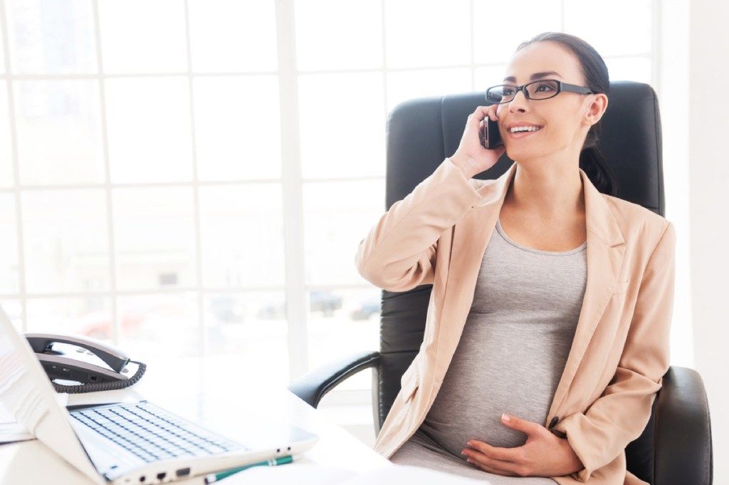 raskaana oleva nainen puhelimessa työpöydällään, toimiston etiketti