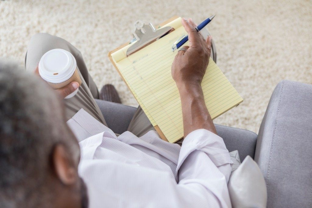mees kirjutab oma eesmärkide nimekirja üles, hoides samal ajal kohvitassile minekut