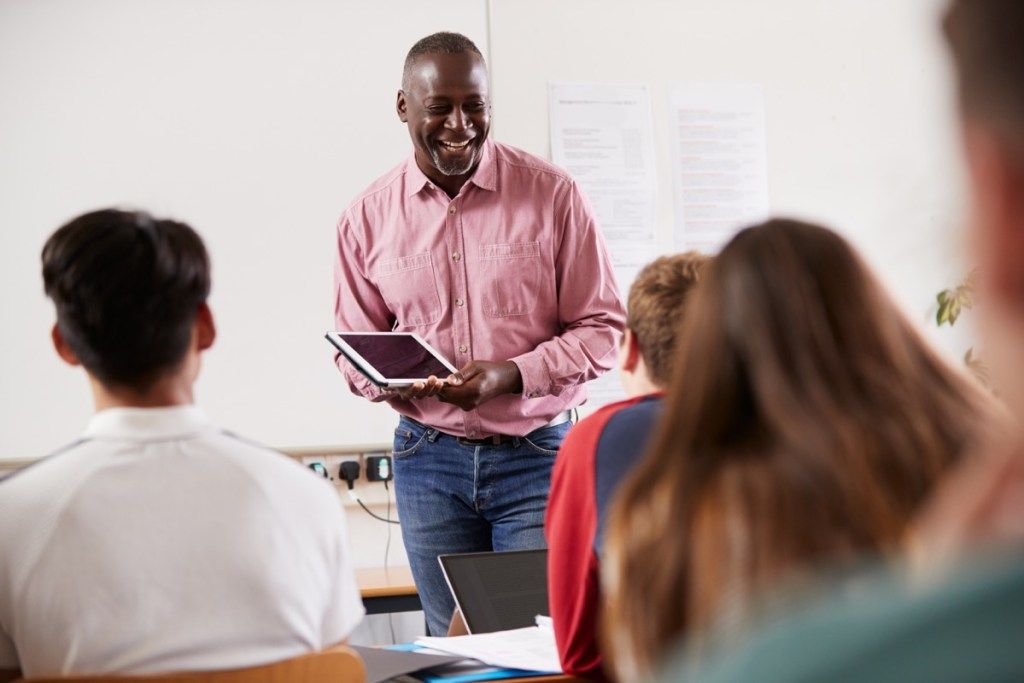 Musta opettaja hymyilee ja opettaa vanhempia opiskelijoita