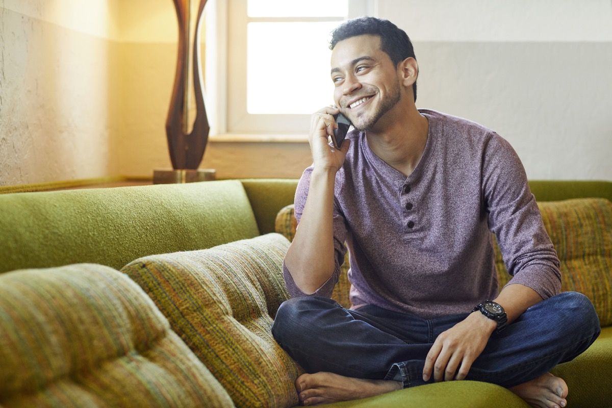 ung mand lykkeligt chatter i telefonen i sofaen