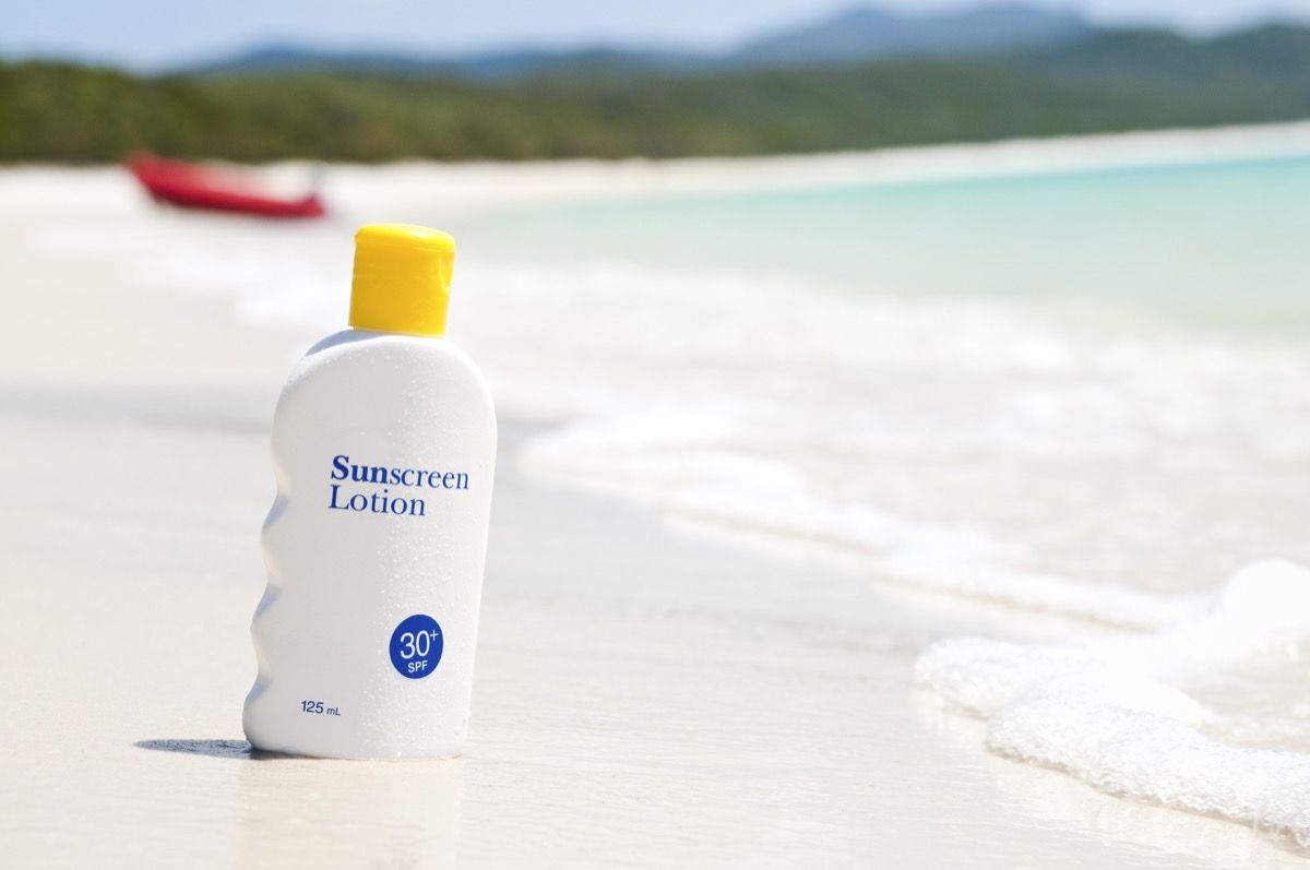 Een fles zonnebrandcrème op een idyllisch strand.