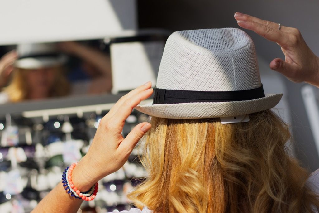 Vrouw probeert op een hoed op de markt.
