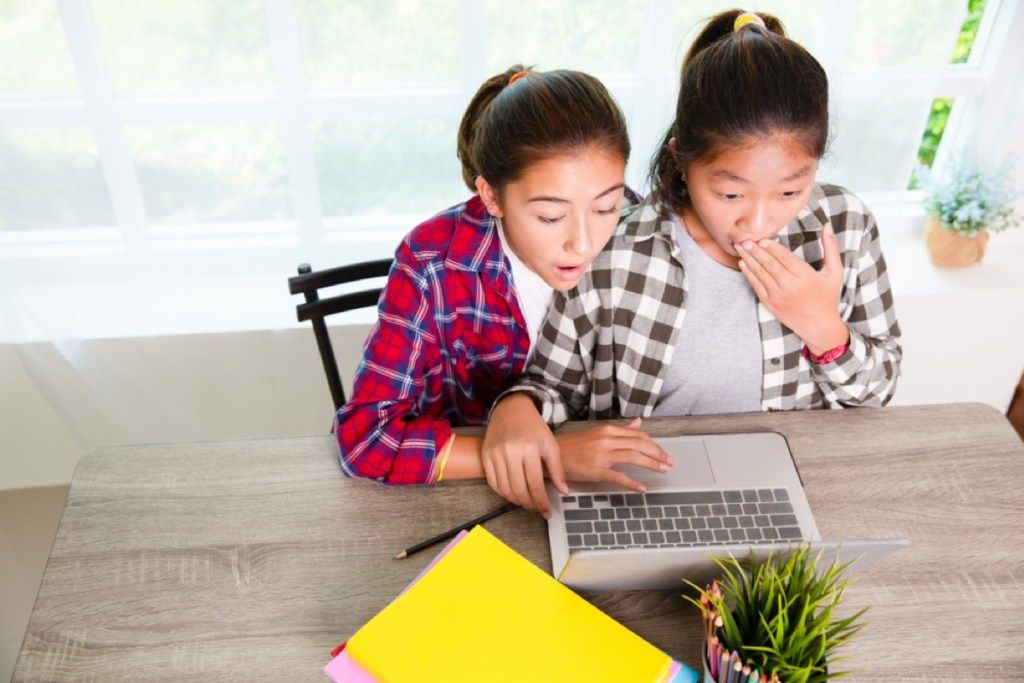 فتاتان صغيرتان تنظران إلى شاشة الكمبيوتر المحمول ، الأبوة والأمومة أصعب