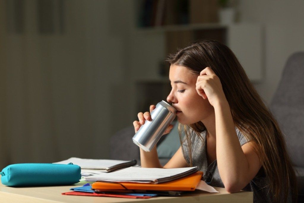 tiener die uit een blik drinkt tijdens het studeren, ouderschap is moeilijker