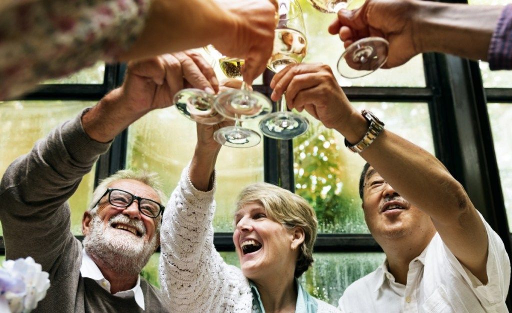 група възрастни хора, пиещи тост с шампанско
