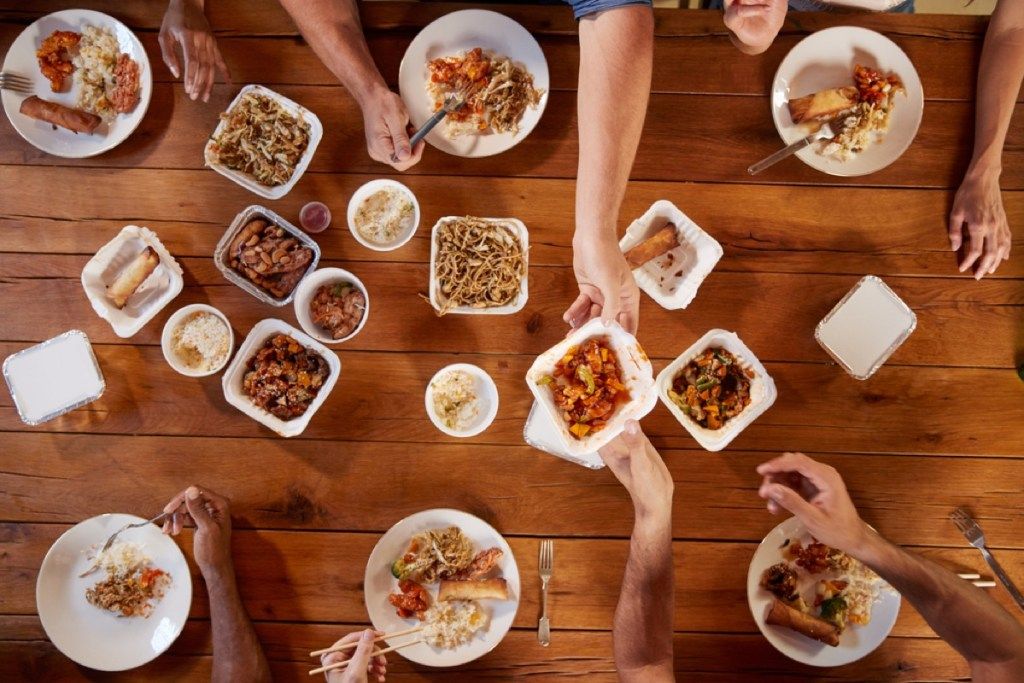 食べ物を求めてテーブルを横切って手を伸ばす人々、エチケットの間違い